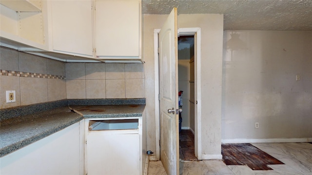 4618 Mallow St, Houston, TX 77051 - kitchen featuring light marble finish flooring, white cabinets, tasteful backsplash, dark countertops, and a textured ceiling