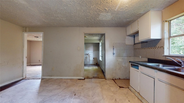 4618 Mallow St, Houston, TX 77051 - kitchen featuring white cabinetry, a sink, dark countertops, and a textured ceiling