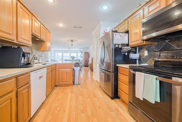 3663 Nasa Pkwy Unit 601, Seabrook, TX 77586 - kitchen with stainless steel appliances, a sink, light wood-style flooring, light countertops, and a peninsula