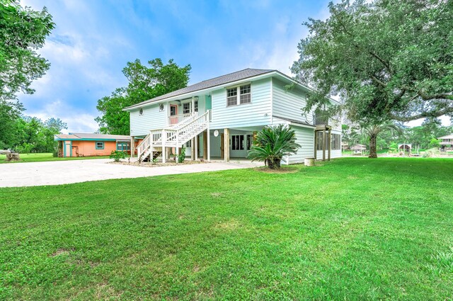 383 County Road 296, Sargent, TX 77414 - coastal inspired home featuring concrete driveway, a carport, stairway, and a front yard