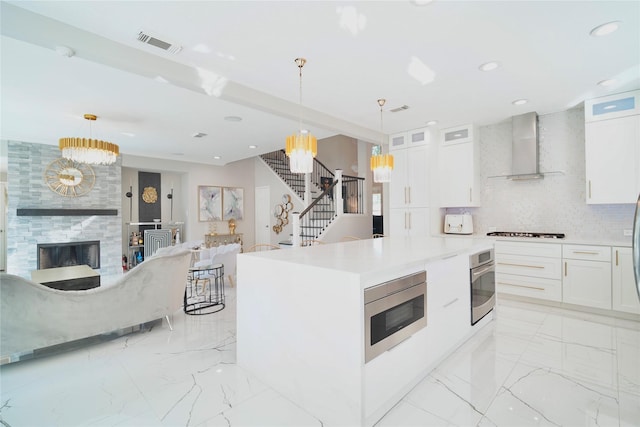5515 E Terrace Gable Cir, Katy, TX 77494 - kitchen featuring wall chimney exhaust hood, appliances with stainless steel finishes, a chandelier, white cabinets, and open floor plan