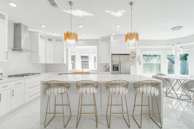 5515 E Terrace Gable Cir, Katy, TX 77494 - kitchen with appliances with stainless steel finishes, a chandelier, wall chimney range hood, light marble finish floors, and recessed lighting