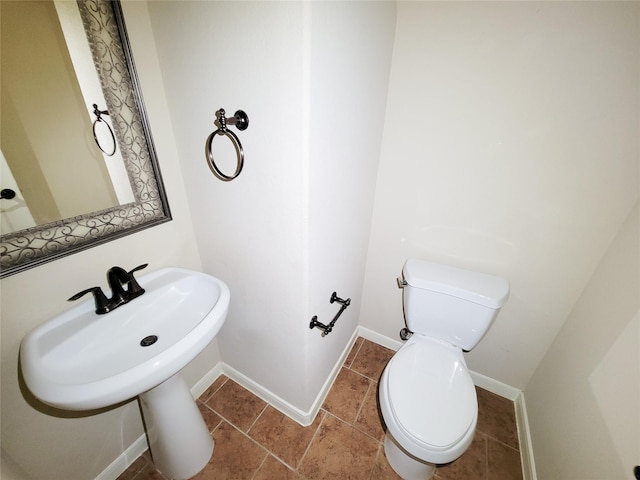 half bathroom featuring toilet, tile patterned floors, and baseboards