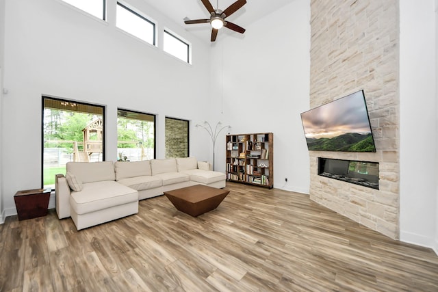 17355 Camillia Trl, Conroe, TX 77302 - living room with a high ceiling, ceiling fan, a stone fireplace, wood finished floors, and baseboards