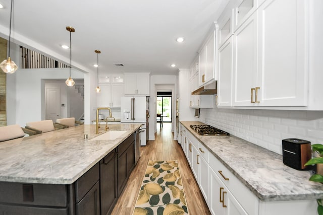 17355 Camillia Trl, Conroe, TX 77302 - kitchen featuring a sink, stainless steel appliances, light wood-style flooring, white cabinets, and tasteful backsplash