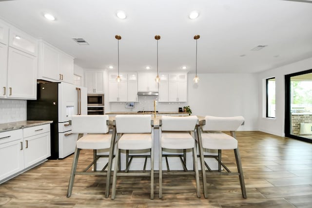 17355 Camillia Trl, Conroe, TX 77302 - kitchen featuring stainless steel microwave, white fridge with ice dispenser, decorative backsplash, white cabinetry, and recessed lighting