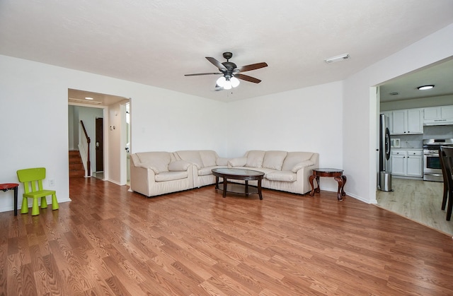 16023 Mission Glen Dr, Houston, TX 77083 - living area with ceiling fan, light wood finished floors, stairway, and baseboards