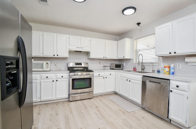 16023 Mission Glen Dr, Houston, TX 77083 - kitchen featuring appliances with stainless steel finishes, a sink, under cabinet range hood, light countertops, and light wood-type flooring