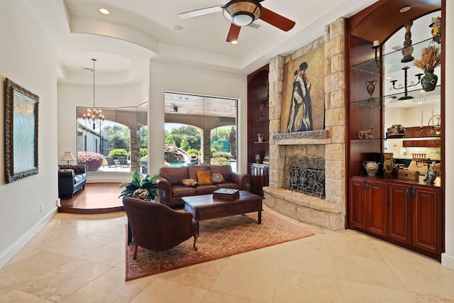 2602 Britton Ridge Dr, Katy, TX 77494 - living room featuring a tray ceiling, built in features, a stone fireplace, a ceiling fan, and light tile patterned floors