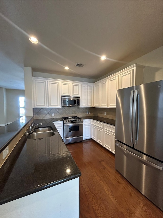2333 Ann St, Houston, TX 77003 - kitchen with stainless steel appliances, a sink, white cabinets, a peninsula, and recessed lighting