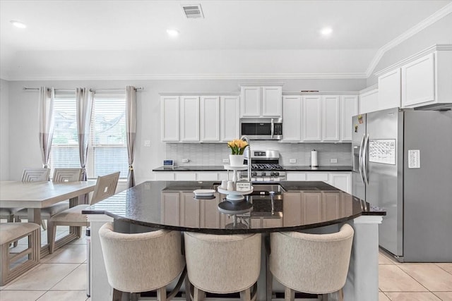 1915 Hays Ranch Dr, Richmond, TX 77469 - kitchen featuring appliances with stainless steel finishes, light tile patterned floors, a kitchen bar, ornamental molding, and recessed lighting