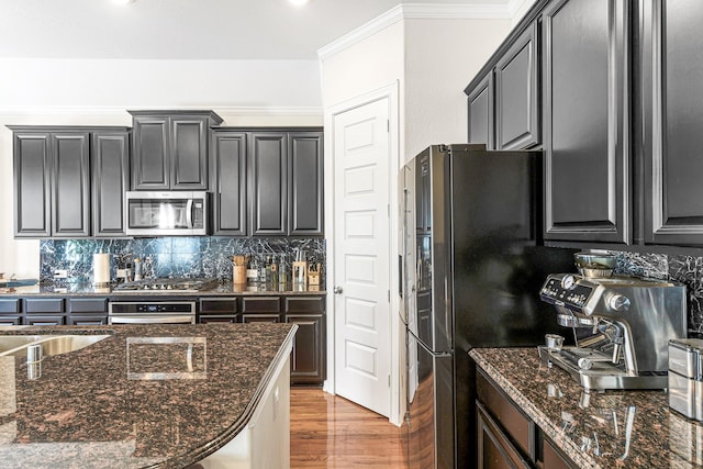 2003 Highland Meadows Dr, Pearland, TX 77089 - kitchen with appliances with stainless steel finishes, tasteful backsplash, light wood-style floors, dark stone countertops, and ornamental molding