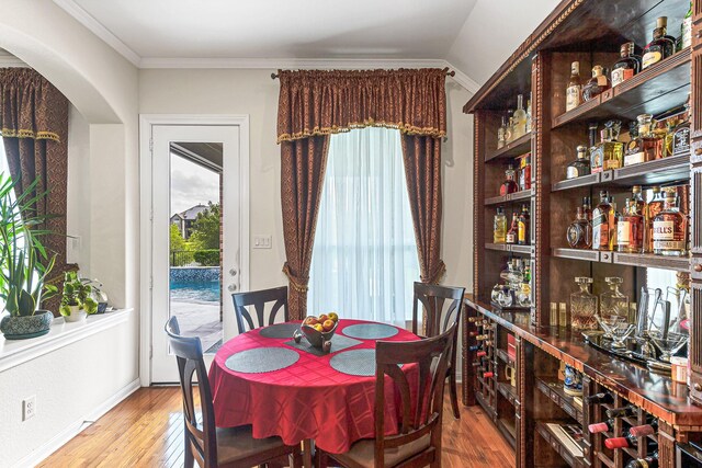 2003 Highland Meadows Dr, Pearland, TX 77089 - dining area featuring wood finished floors, arched walkways, a bar, crown molding, and baseboards