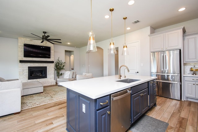 1907 Creekwood Cv, Missouri City, TX 77459 - kitchen with appliances with stainless steel finishes, a sink, blue cabinetry, light wood-style floors, and recessed lighting