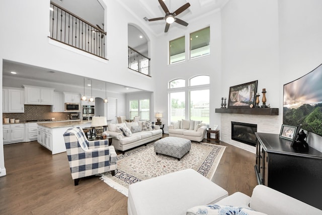 6510 Kangaroo Point Ln, Sugar Land, TX 77479 - living area with a glass covered fireplace, a ceiling fan, a towering ceiling, dark wood-style floors, and recessed lighting