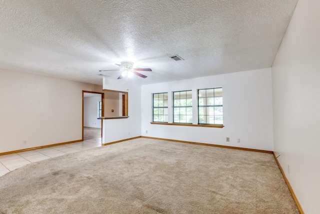 5718 Sheppard Rd, Baytown, TX 77521 - empty room with light colored carpet, a ceiling fan, baseboards, a textured ceiling, and light tile patterned floors