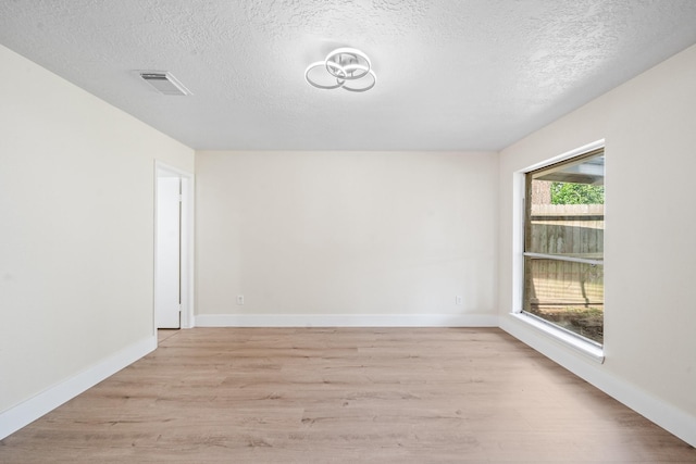 11115 Maple Rock Dr, Humble, TX 77396 - empty room featuring light wood-style floors, a textured ceiling, and baseboards