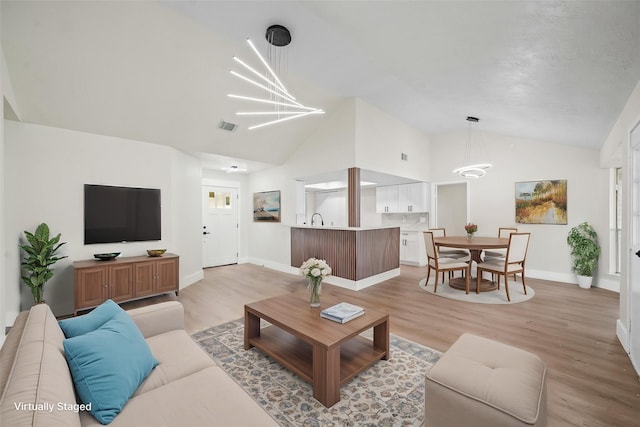 11115 Maple Rock Dr, Humble, TX 77396 - living room with vaulted ceiling, baseboards, light wood-type flooring, and a chandelier