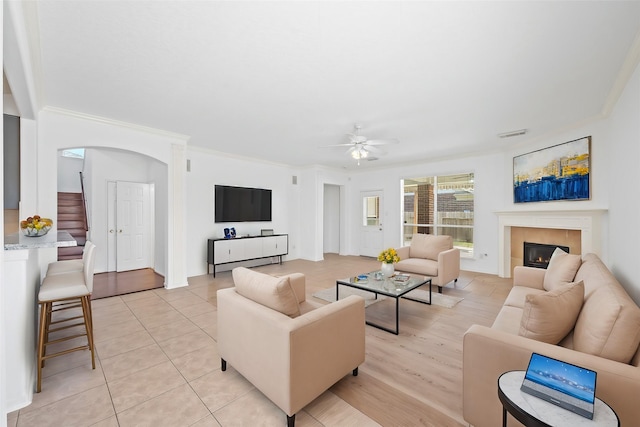 15026 Magnoliabough Pl, Cypress, TX 77429 - living room with crown molding, a ceiling fan, arched walkways, a fireplace, and light tile patterned floors