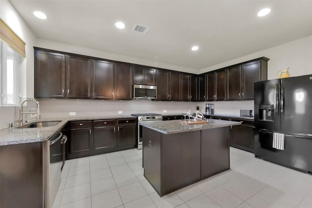 5335 Ivory Glass Dr, Katy, TX 77493 - kitchen with appliances with stainless steel finishes, a sink, light stone counters, dark brown cabinets, and light tile patterned floors