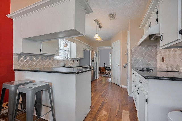21226 Park Bend Dr, Katy, TX 77450 - kitchen with a sink, stainless steel fridge, dark countertops, under cabinet range hood, and a peninsula