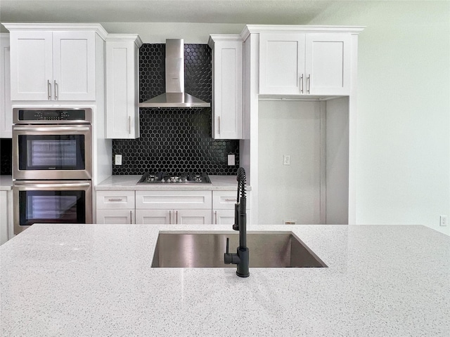 9630 Landry Blvd, Spring, TX 77379 - kitchen with wall chimney range hood, stainless steel appliances, a sink, white cabinets, and backsplash