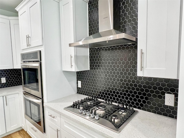 9630 Landry Blvd, Spring, TX 77379 - kitchen with wall chimney exhaust hood, stainless steel appliances, decorative backsplash, white cabinets, and light stone countertops