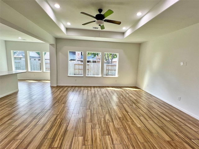 9630 Landry Blvd, Spring, TX 77379 - unfurnished living room featuring a raised ceiling, wood finished floors, plenty of natural light, baseboards, and recessed lighting