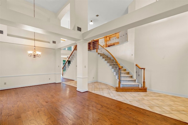 14306 Medlowe Ct, Cypress, TX 77429 - unfurnished living room featuring stairs, a high ceiling, a chandelier, baseboards, and wood finished floors