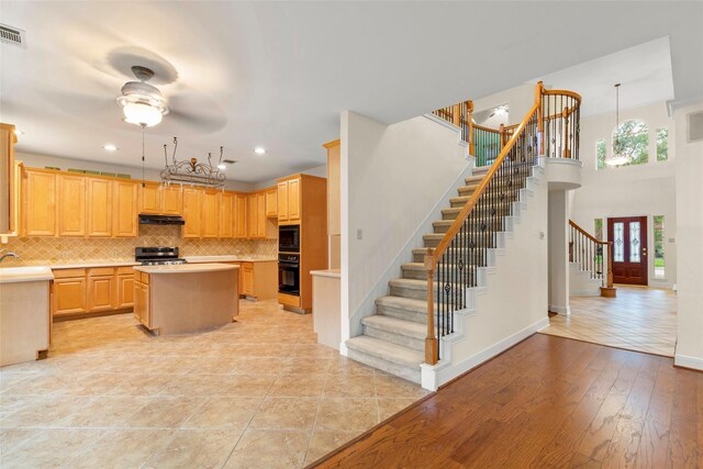 14306 Medlowe Ct, Cypress, TX 77429 - kitchen with black appliances, under cabinet range hood, light countertops, a kitchen island, and decorative backsplash