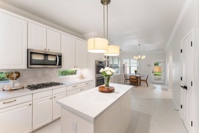 6 Cranberry Bnd, The Woodlands, TX 77381 - kitchen with appliances with stainless steel finishes, crown molding, decorative backsplash, white cabinetry, and a center island