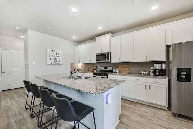 12738 Beatrice Terrace Dr, Humble, TX 77346 - kitchen with appliances with stainless steel finishes, a sink, white cabinetry, light wood-style flooring, and recessed lighting