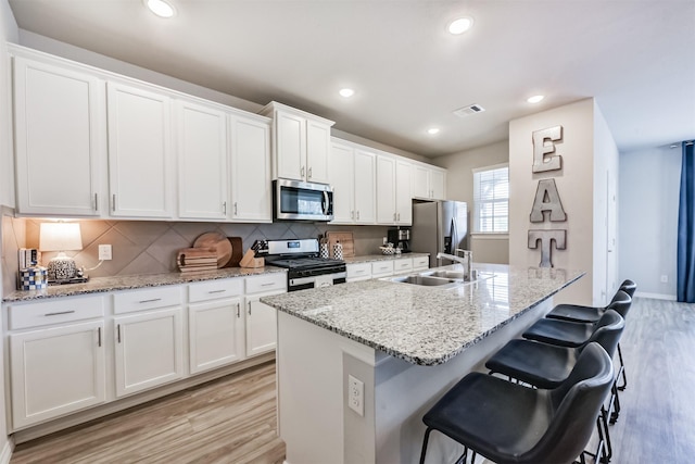 12738 Beatrice Terrace Dr, Humble, TX 77346 - kitchen with stainless steel appliances, light wood-style flooring, a kitchen breakfast bar, white cabinets, and recessed lighting