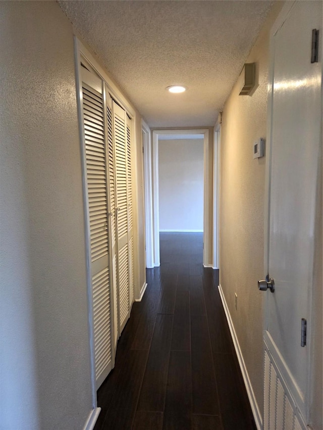 12029 Greenwood Forest Dr, Houston, TX 77066 - corridor featuring a textured ceiling, baseboards, dark wood finished floors, a textured wall, and recessed lighting