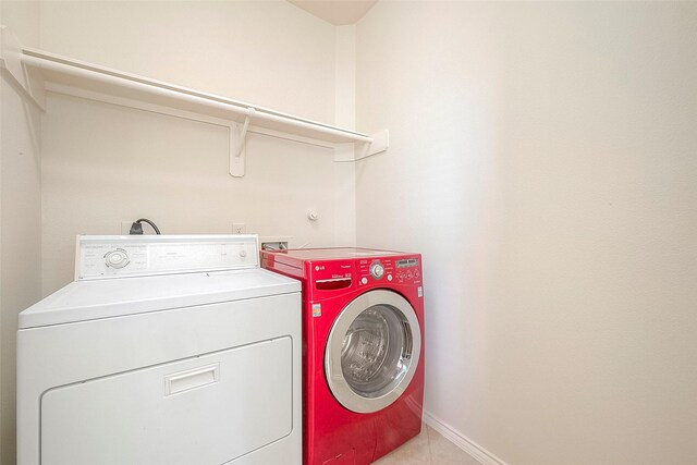 1119 Palmer St, Houston, TX 77003 - laundry area with washer and clothes dryer, light tile patterned flooring, and baseboards