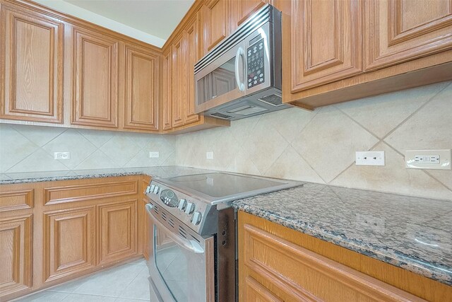 1119 Palmer St, Houston, TX 77003 - kitchen featuring appliances with stainless steel finishes, stone countertops, tasteful backsplash, and light tile patterned floors
