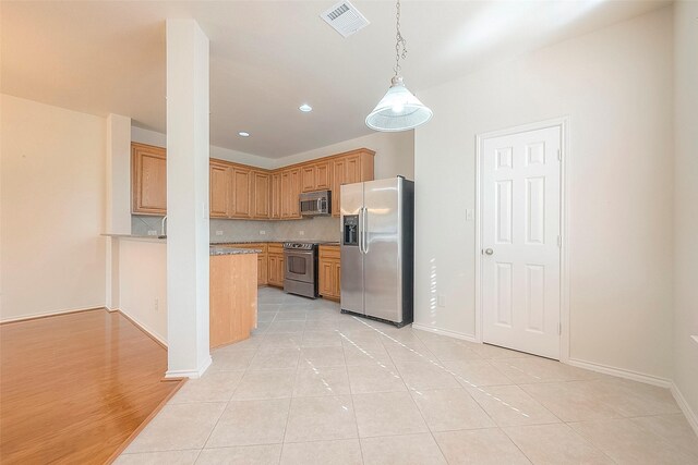 1119 Palmer St, Houston, TX 77003 - kitchen featuring appliances with stainless steel finishes, decorative backsplash, decorative light fixtures, light countertops, and light tile patterned floors