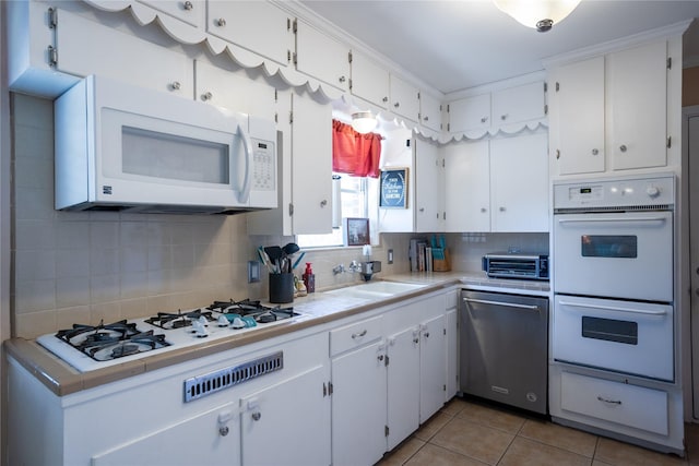 1803 Foxwood Rd, Houston, TX 77008 - kitchen with white appliances, a sink, white cabinetry, tasteful backsplash, and light tile patterned floors
