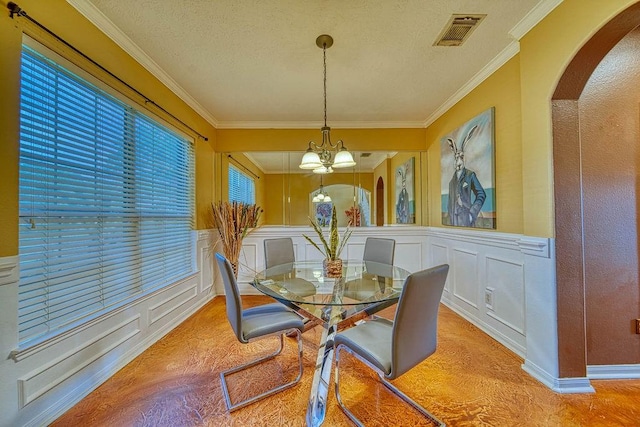 1114 Carriage Ct, Seabrook, TX 77586 - dining space featuring a chandelier, arched walkways, a decorative wall, crown molding, and a wainscoted wall