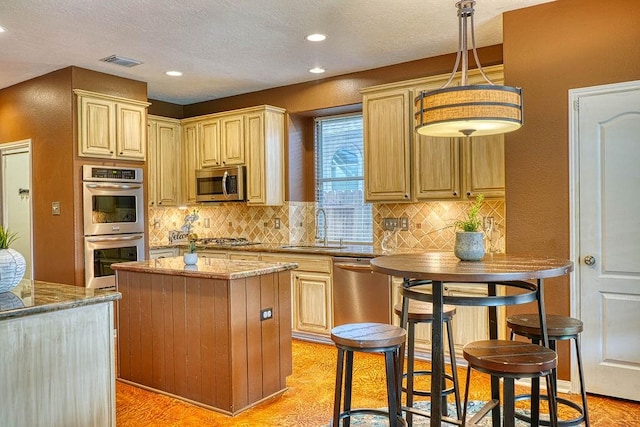 1114 Carriage Ct, Seabrook, TX 77586 - kitchen with a sink, stainless steel appliances, a center island, decorative backsplash, and light stone countertops