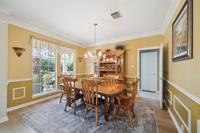 2 Slatestone Cir, The Woodlands, TX 77382 - dining area with ornamental molding, wood finished floors, a chandelier, and a wainscoted wall