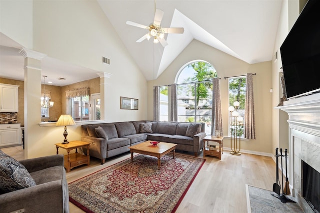 2 Slatestone Cir, The Woodlands, TX 77382 - living room featuring a fireplace, light wood finished floors, a ceiling fan, decorative columns, and baseboards