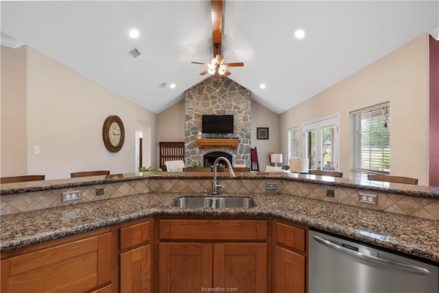 6443 Hardy Weedon Rd, College Station, TX 77845 - kitchen featuring stainless steel dishwasher, a sink, a ceiling fan, dark stone countertops, and a fireplace
