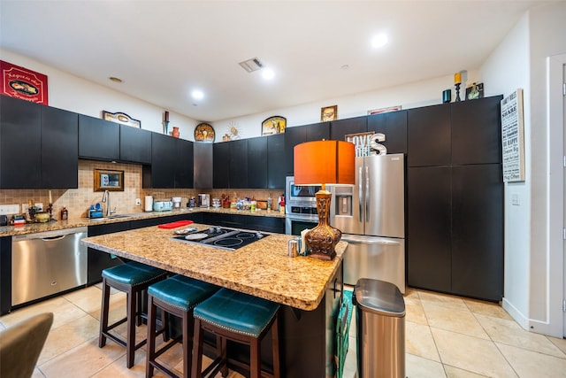 11434 Ketch Ct, Willis, TX 77318 - kitchen with appliances with stainless steel finishes, dark cabinets, a sink, a breakfast bar area, and tasteful backsplash