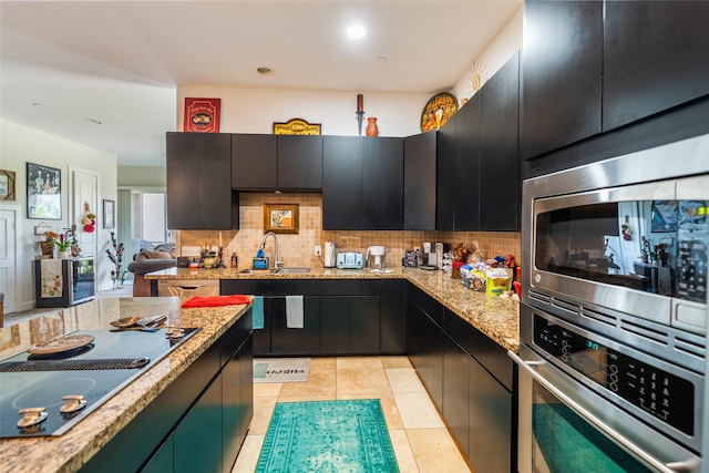 11434 Ketch Ct, Willis, TX 77318 - kitchen featuring appliances with stainless steel finishes, a sink, dark cabinets, and backsplash