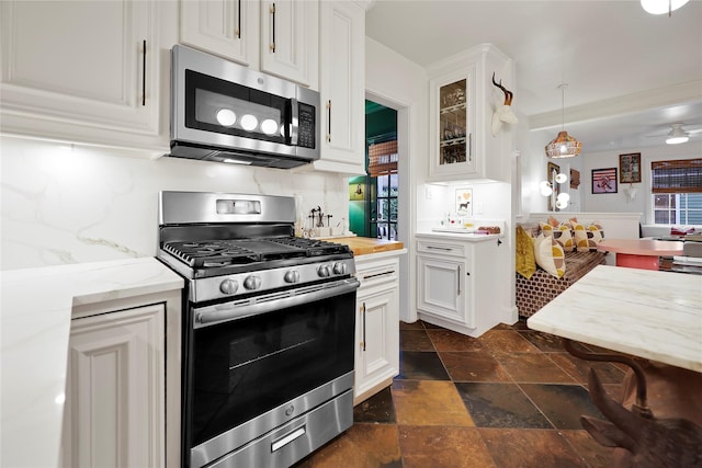 1305 Postoffice, Galveston, TX 77550 - kitchen with stainless steel appliances, white cabinetry, stone tile flooring, glass insert cabinets, and ceiling fan