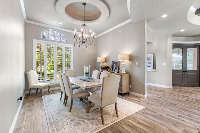 11 Turtle Cove Ct, Kingwood, TX 77346 - dining area featuring baseboards, a tray ceiling, light wood-style floors, a chandelier, and ornamental molding