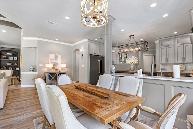 11 Turtle Cove Ct, Kingwood, TX 77346 - dining room with a chandelier, recessed lighting, arched walkways, light wood-style flooring, and crown molding