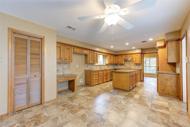 538 Everington Dr, Katy, TX 77450 - kitchen with a kitchen island, decorative backsplash, under cabinet range hood, dishwasher, and brown cabinets