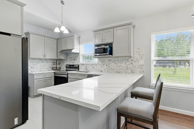 953 Rd 5606, Cleveland, TX 77327 - kitchen with stainless steel appliances, gray cabinets, vaulted ceiling, a peninsula, and a sink